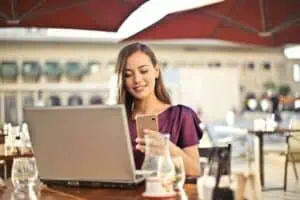 a woman sitting at a table with a laptop and a phone