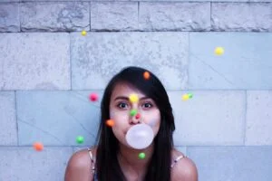 a woman blowing bubble with gumballs