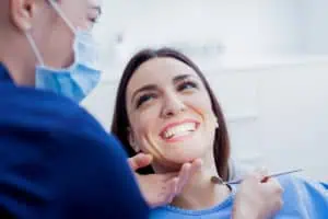 a woman smiling with a dentist in the background