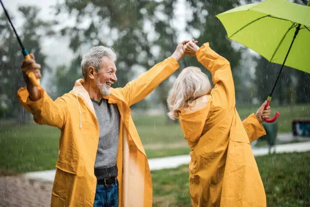 a man and woman in raincoats holding umbrellas