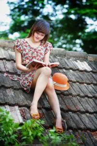 a woman sitting on a roof reading a book