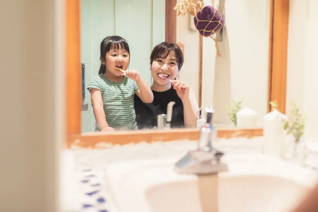 a woman and child brushing their teeth in a bathroom