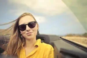 a woman in sunglasses in a convertible