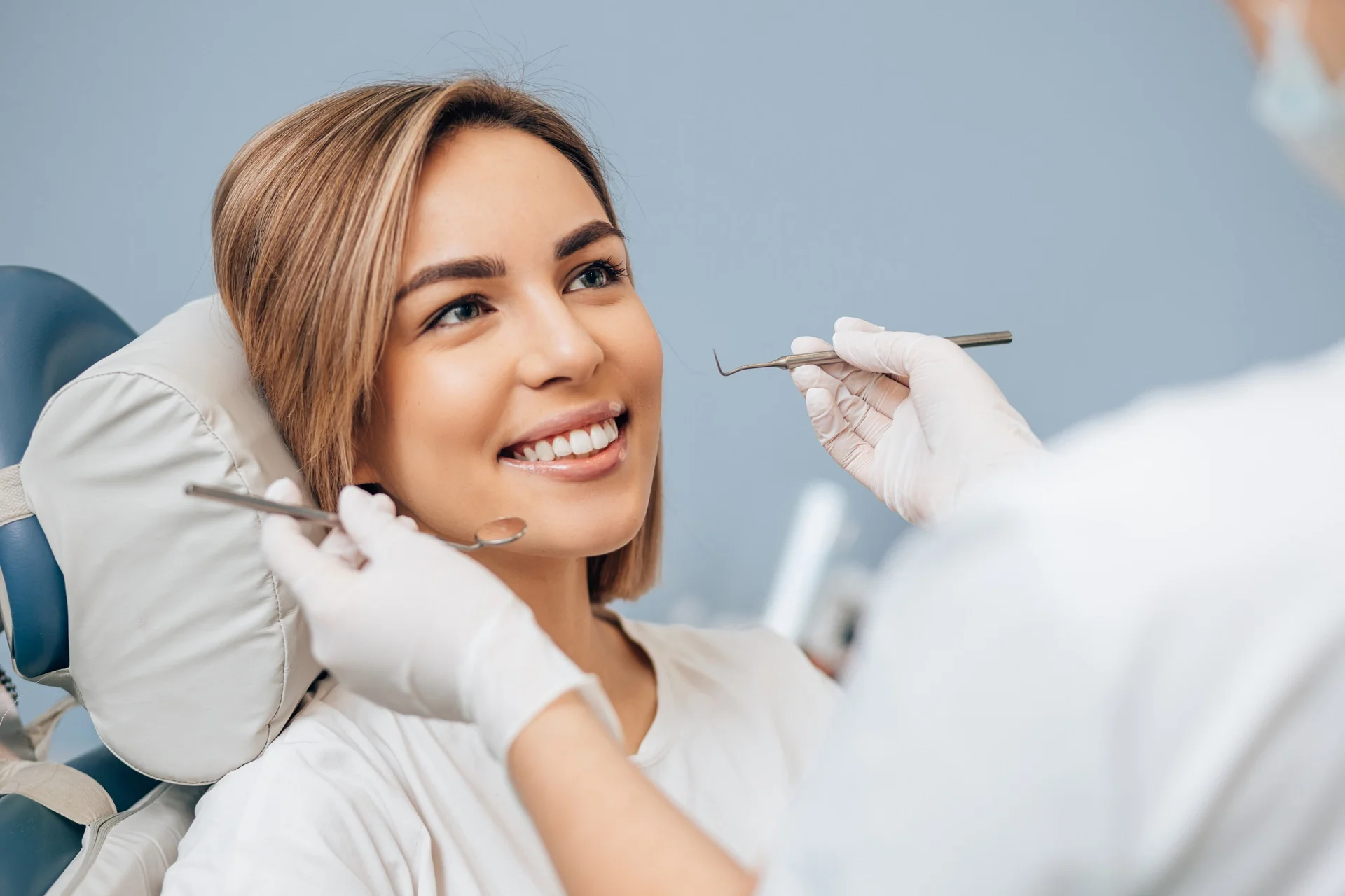 a woman smiling while holding a dentist tool