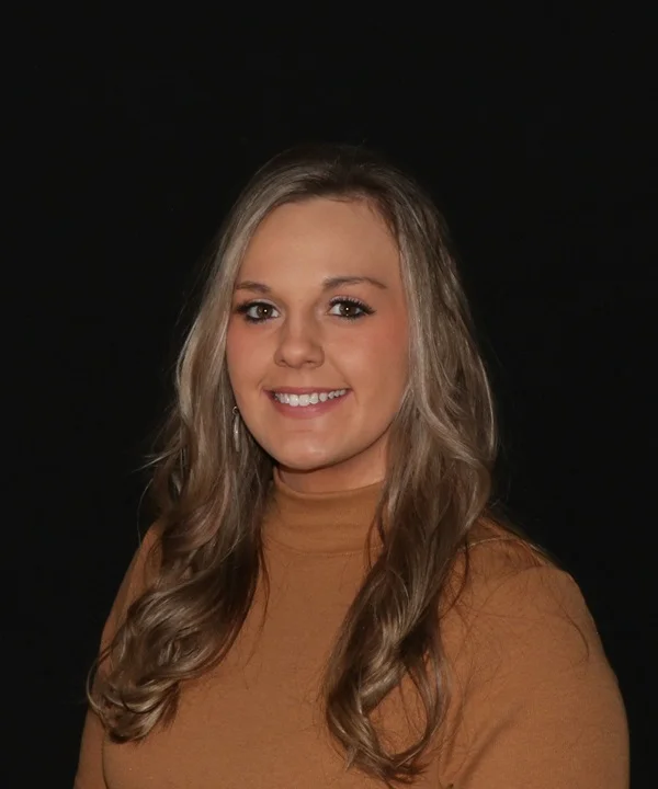 a woman with long hair wearing a brown turtleneck