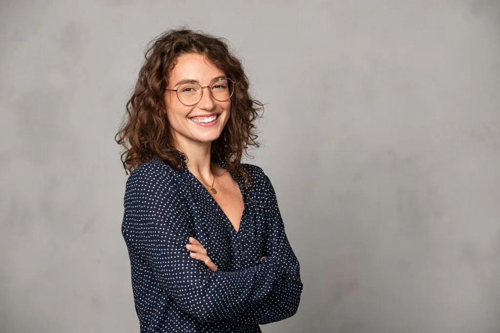 a woman with curly hair wearing glasses and a polka dot shirt
