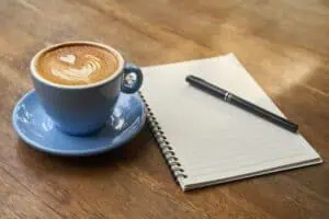 a cup of coffee and a pen on a notebook